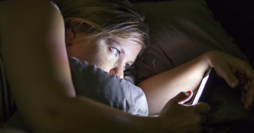 Mulher usa celular na cama. Foto: Reprodução de Internet