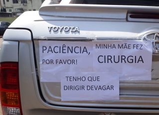 Mulher coloca cartazes em carro para justificar lentidão em viagem. Foto: Reprodução de Internet