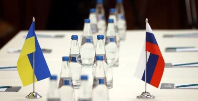 Garrafas de água em uma mesa em meio as bandeiras da Ucrânia e da Rússia. Foto: Reprodução/Ministério das Relações Exteriores da República da Bielorrússia