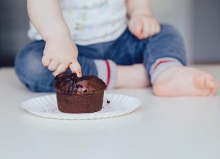 Criança colocando a mão em doce de chocolate. Foto: Piksit