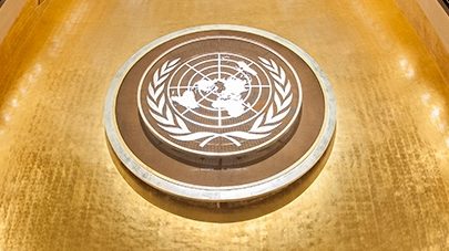 Emblema da ONU e pódio no Salão da Assembleia Geral. Foto da ONU/Cia Pak